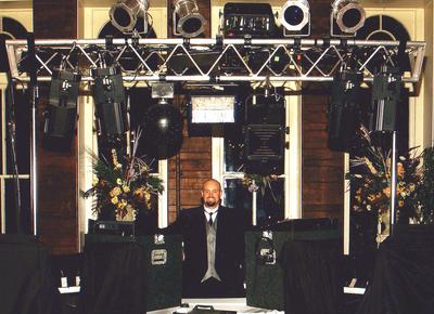 This is Emcee Sean Hearn in Eureka Springs at the Crescent Hotel in the early 2000s, standing under his immense lighting array that included several par cans, a 2000 watt black light, 4 Martin 812 intelligent scanners, an Atomic Strobe, a Martin Rapture and a fog machine. These lights paired with his Peavey SP2 speakers and 118 Black Widow sub woofer is a crystal clear sounding and visually stunning display.