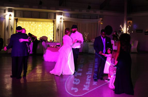 Many dancers share the floor at a wedding reception in Holiday Island Arkansas. The couple's name is monogrammed on the floor in lights.